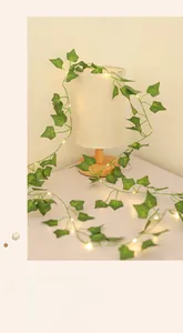 Detail of LED eucalyptus leaf fairy lights wrapped around a desk lamp for decor