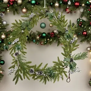 Close-up of a festive Christmas wreath featuring green pine needles and silver berries