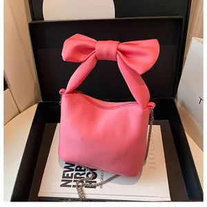 Detail of pink satin handbag with large bow handle and silver chain strap for women