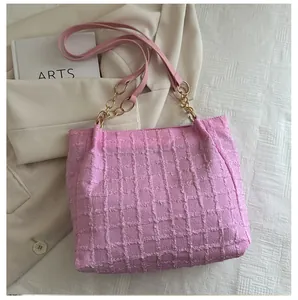 Close-up of pink tweed tote bag with waffle texture and gold chain detail on fabric
