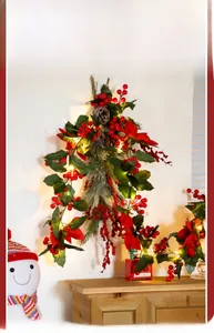 Hanging Christmas garland with red berries, pine cones and warm LED lights on a wall