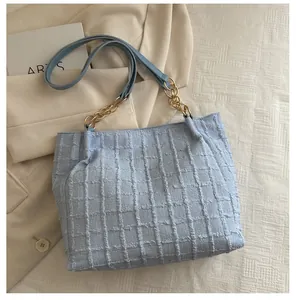 Detail of light blue checkered wool tote bag showing texture and metal chain strap