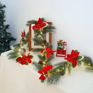 Close-up of lighted Christmas wreath with pine needles, red poinsettia and pine cones