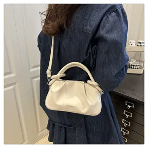 Détail d'un sac nuage plissé crème avec poignée nouée et bandoulière amovible