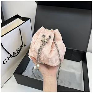 Vue détaillée du sac seau en dentelle rose brodée avec chaîne et détails en perles