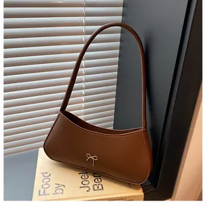 Detailansicht der braunen Schultertasche mit Schleife auf Vintage-Büchern