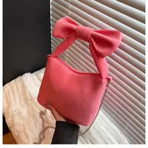 Detail of hot pink satin bag with oversized bow handle and silver chain strap