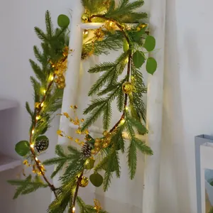 Close-up of lighted Christmas garland with gold berries and pine cones on a wooden ladder