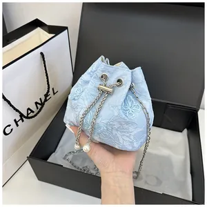 Détail du sac seau en dentelle bleu clair avec broderie papillon et perles