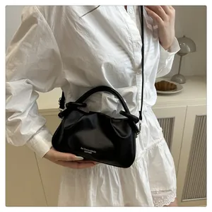 Détail du sac nuage plissé en cuir noir avec poignée cylindrique et bandoulière élégante