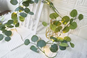 Détail de guirlandes LED chaudes brillant sur des feuilles d'eucalyptus artificielles