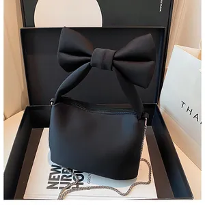 Close-up of a black matte bow-knot handbag with a silver chain in a stylish gift box