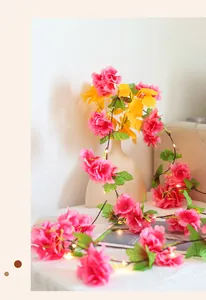 Close-up of pink cherry blossom LED copper string lights wrapping a vase for home decor