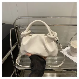Vue détaillée du sac nuage crème avec poignée tressée et bandoulière amovible sur étagère