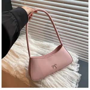 Detail einer rosa Halbmond-Umhängetasche mit kleiner Metallschleife und schmalem Gurt