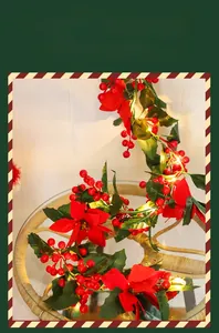 Close-up of festive Christmas garland with red poinsettias, holly berries, and LED lights
