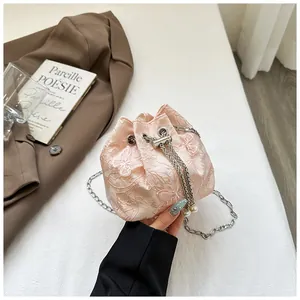 Détail du sac seau en dentelle rose avec broderie papillon et cordon de serrage perlé