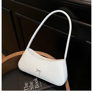 Details einer weißen Schultertasche aus Leder mit silberner Schleifenschnalle im Design