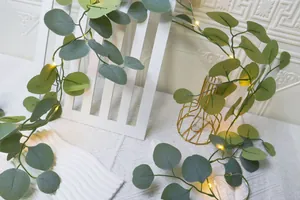 Détail de guirlande d'eucalyptus artificiel avec LED chaudes sur clôture blanche