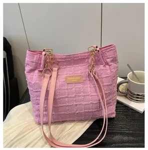 Close-up of pink bubble-textured tote bag with leather logo tag and gold chain strap