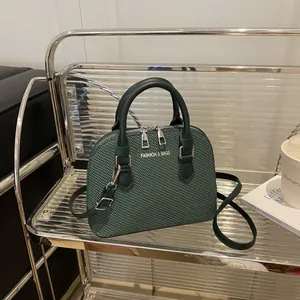 Dark green shell-shaped handbag with woven texture and adjustable shoulder strap
