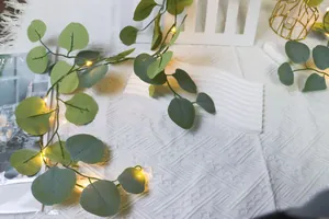 Détail de guirlandes LED chaudes entrelacées de feuilles d'eucalyptus sur tricot blanc