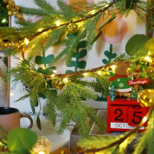 Detail of warm white LED string lights on pine branches with golden bells