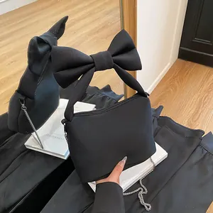 Fashionable black canvas handbag with a large bow handle and silver chain strap