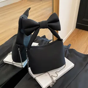 Fashionable black canvas shoulder bag with large bow detail and silver chain strap