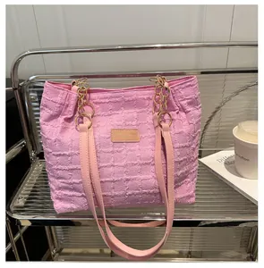Macro shot of pink textured tote bag with golden metal rings and leather straps