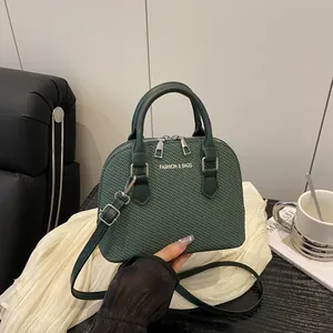 Dark green shell handbag with crocodile texture and fashion logo shown in lifestyle setting