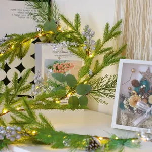 Close-up of lighted Christmas pine needle garland with silver berries and pinecones