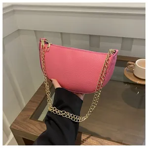 Detailansicht der pinkfarbenen Halbmondtasche mit Kieselmaserung und goldener Kette