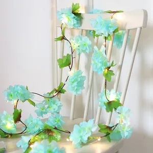 LED cherry blossom vine string lights with blue fabric flowers and green leaves on white chair