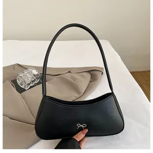 Detailansicht einer schwarzen matten Ledertasche mit einer silbernen Metallschleife