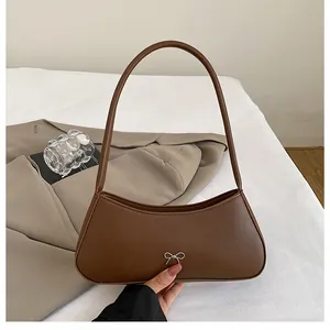 Detailaufnahme des silbernen Schleifenanhängers auf der braunen matten Ledertasche