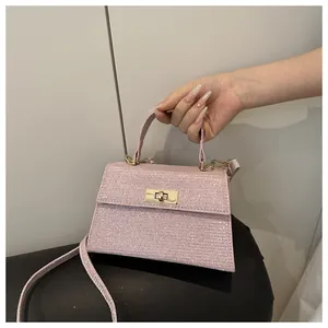 Detail of pink glitter handbag featuring a golden turn-lock closure and slim strap