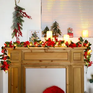 Christmas garland with red berries, poinsettia flowers and warm LED lights on a wooden mantel