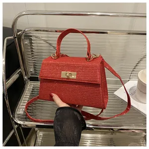 Detail of red sequined handbag featuring a golden rectangular twist lock and handle