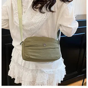 Detailed view of olive green nylon crossbody bag with adjustable wide strap and M logo