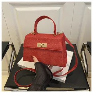Detail of red glitter fabric crossbody bag with golden rotary lock and textured finish