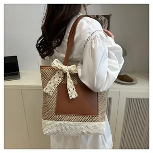 Detail of woven straw tote bag with brown leather pocket and lace bow on a model