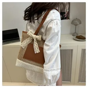Detail of woven straw tote bag with brown leather pocket and large cream lace bow