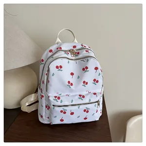 Detailed view of white cherry print backpack with large front pocket on wooden table