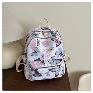 Detailed view of women's floral backpack featuring pastel butterfly prints and gold zippers