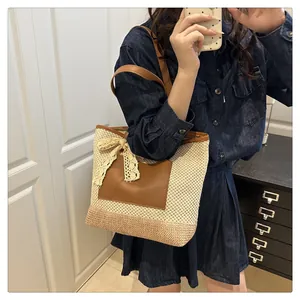 Detail of woven straw tote bag with brown PU leather pocket and white lace bow decoration