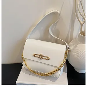 Detailed close-up of white leather flap handbag with gold metal clasp and chain handle