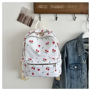 Detail of white canvas backpack with cherry print featuring double zippers and pockets