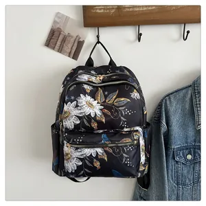 Detail of water-resistant black backpack with daisy and bird print and gold metal zippers