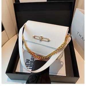 Detail view of white leather handbag with golden rectangular clasp in elegant gift box